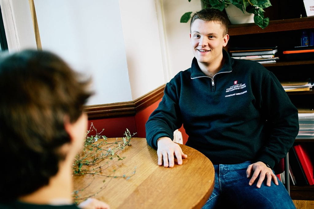 Hunter Wienke sits at a table with one of his students.