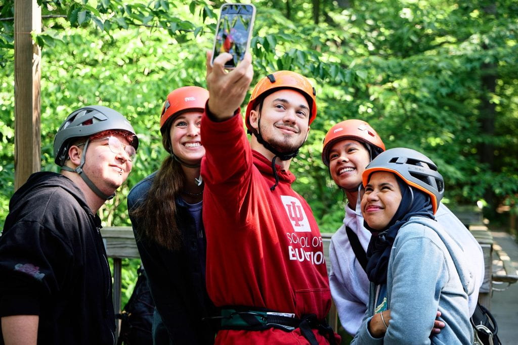 Camp counselors wearing helmets pose for a group selfie at Bradford Woods.
