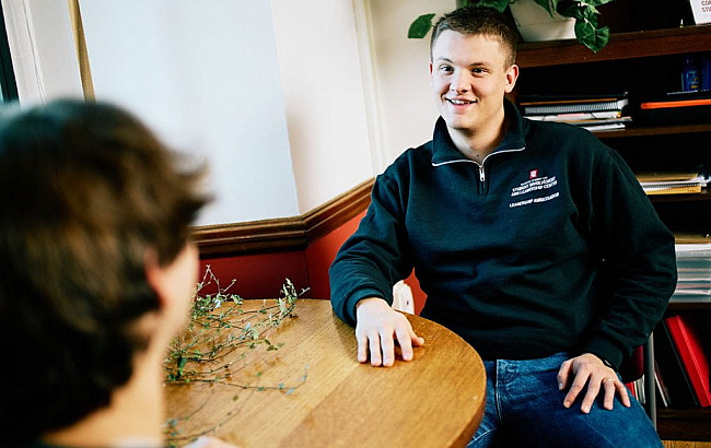 Hunter Wienke sits at a table with one of his students.