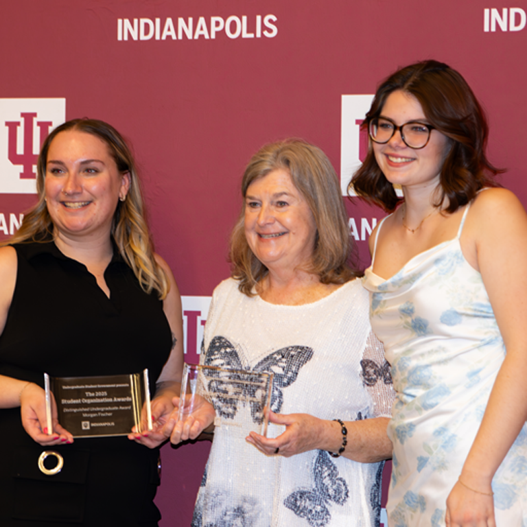 Three women posing for an award.