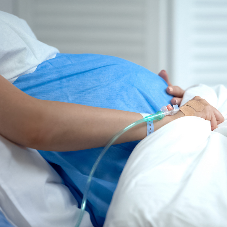 Pregnant woman holding blanket, feeling abdominal pain, risk of miscarriage